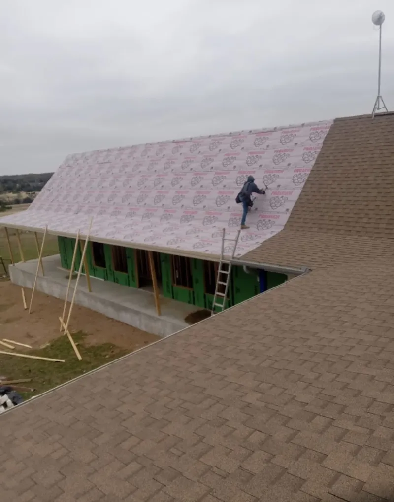 Worker preparing underlayment for a metal roof installation in Batesville